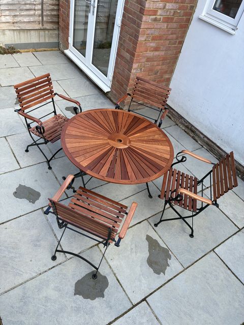 Sapele garden table and four folding chairs on a patio